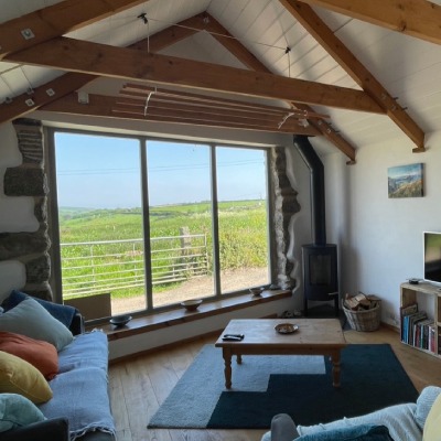 Photo of sitting room at Trengothal Barn holiday retreat with view through large window of fields